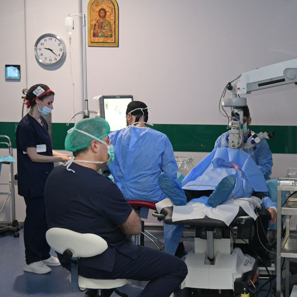 Ομάδα οφθαλμιάτρων και νοσηλευτών σε εξέλιξη μικροχειρουργικής επέμβασης ματιού με προηγμένο μικροσκόπιο και εξειδικευμένο εξοπλισμό